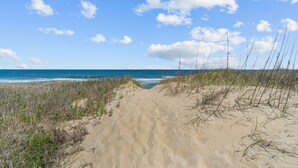 A sandy beach path leading to the ocean with sparse vegetation. - 5381- Sol-T-Escape - Wake to Ocean Views | Oceanfront KDH Condo (Kill Devil Hills)