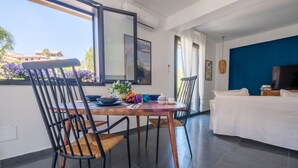 Una sala de estar moderna con comedor, televisor de pantalla plana y vistas al exterior.