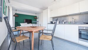 A modern kitchen with white cabinets, a wooden dining table, and wicker chairs.