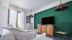 A modern living room with a sofa, a television, wooden cabinet, and a green wall.
