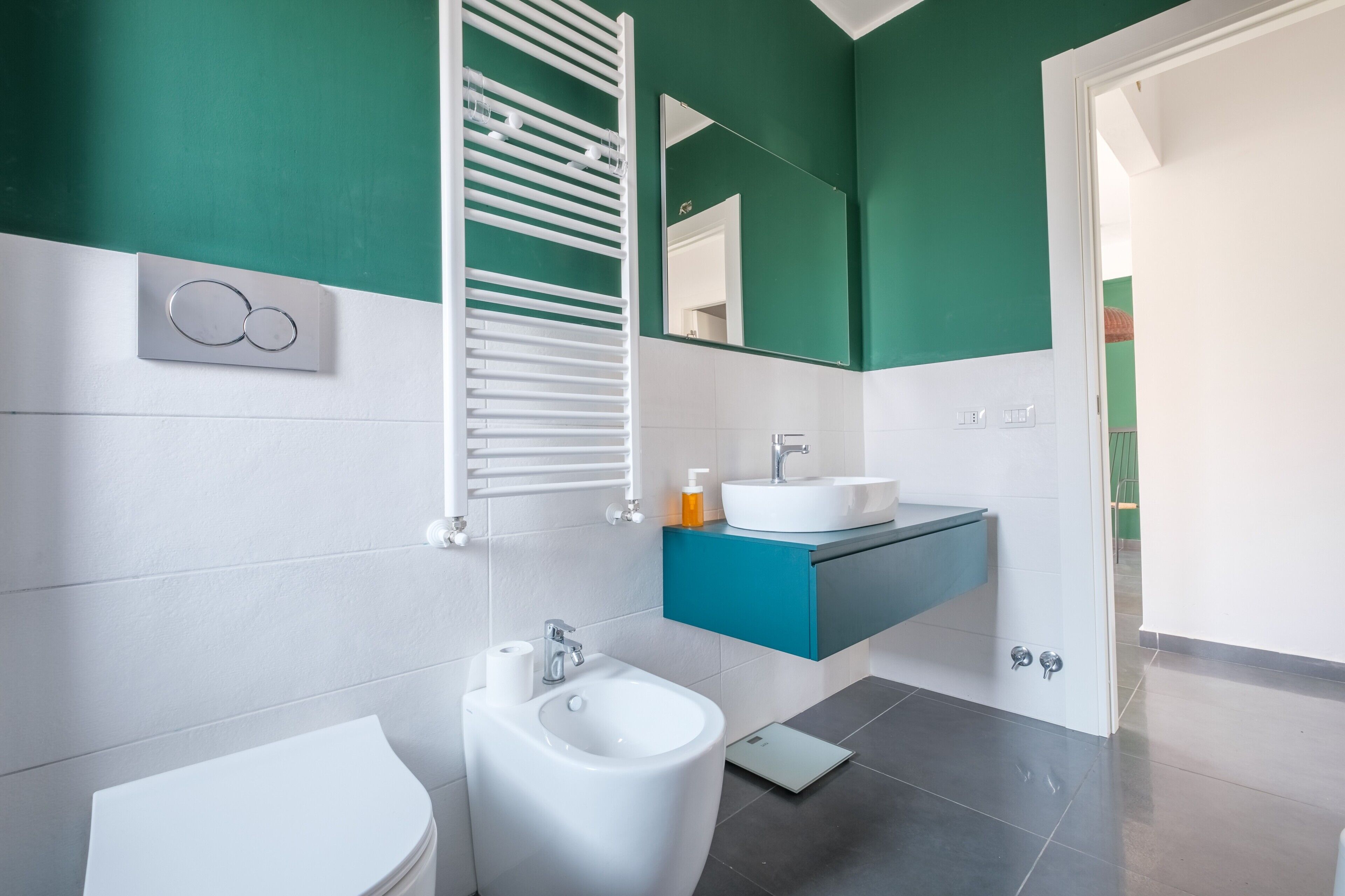 A modern bathroom with a bidet, toilet, and a vanity with a mirror.