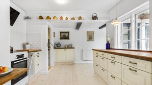A kitchen with white cabinets, a wooden countertop, and a white tiled backsplash. There is a stove, a sink, and a window with a view. - Amazing apartment in Tisvildeleje (Tisvildeleje)