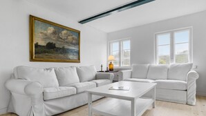 A modern living room with a white sofa, a white coffee table, and a painting on the wall. - Amazing apartment in Tisvildeleje (Tisvildeleje)