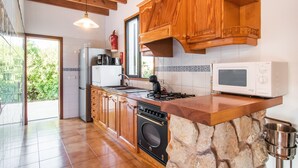 Een keuken met houten kasten, een stenen eiland, een fornuis, een magnetron en een spoelbak.