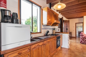 A kitchen with wooden cabinets, a Bosch refrigerator, a coffee maker, a microwave, and a sink.