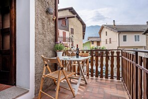Un balcon avec une table et des chaises, une vue sur les maisons voisines et un paysage montagneux en arrière-plan.