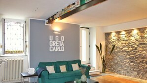 Een woonkamer met een groene bank, een bijzettafeltje, een stenen muur en een radiator.
