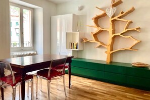 A dining area with a wooden table, red chairs, a green bench, and a wall-mounted wooden tree sculpture. - My Heart in Argegno - My Home in Como (Argegno)