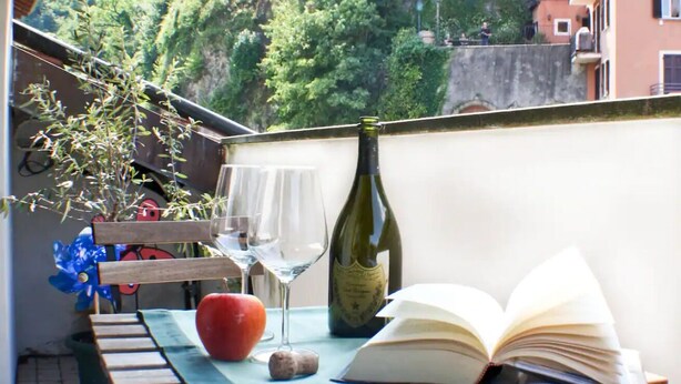 Een balkon met een tafel, een boek, een fles en glazen.