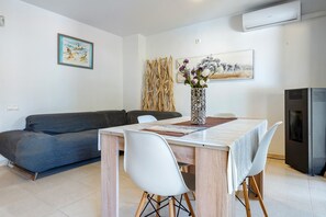 Un salon moderne comprenant un canapé, une table à manger, des chaises, un vase décoratif et des œuvres d’art accrochées aux murs.