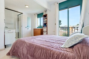 Une chambre à coucher avec un lit, une armoire, un miroir et une fenêtre donnant sur un beau paysage.