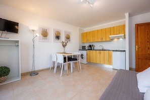 Un espace de vie compact comprenant un coin repas, une kitchenette et un lit.