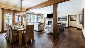 Un vaste espace de vie comprenant une table à manger, des chaises en osier et une cheminée.