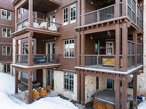 A multi-story wooden building with balconies, stone walls, and outdoor seating.