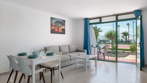 Una sala de estar moderna con comedor, sofá y un amplio ventanal corredera que da a un patio exterior.