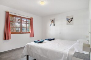 A bedroom with a bed, a window with curtains, and two wall-mounted artworks. - Vacation Home 'Apartamento A 1 Minuto De Playa' with Shared Pool, Private Terrace and Shared Garden (Puerto del Carmen)