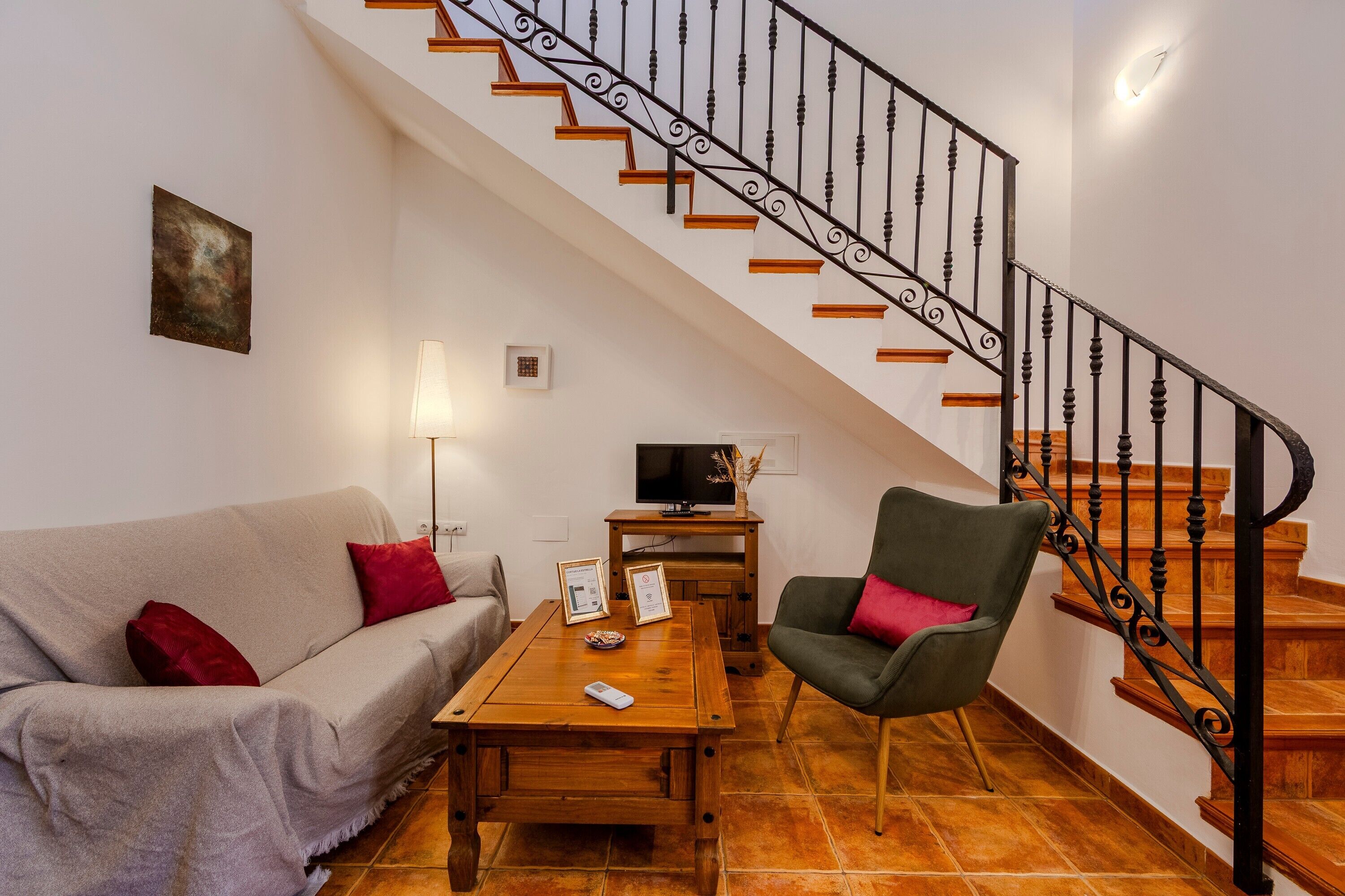 Un salon comprenant un canapé, un fauteuil, une table basse, un téléviseur et un escalier doté d’une rampe.