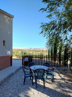 Un patio con mesa y sillas, una cerca de madera y vistas a las montañas.