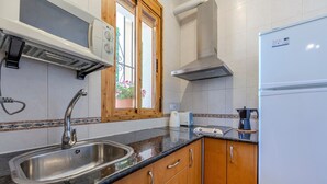 Une cuisine équipée d’un évier en acier inoxydable, de meubles de rangement en bois, d’un four encastré et d’un réfrigérateur.
