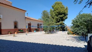 A courtyard with a volleyball net, potted plants, and a building with a tiled roof.