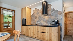 Eine Küche mit Holzausstattung, einem eingebauten Backofen, einer Kaffeemaschine und einer Rückwand aus sechseckigen Fliesen.