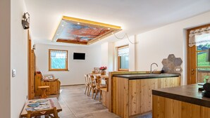 A modern kitchen with wooden cabinetry, a central island, and a dining area with chairs.