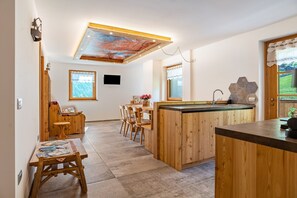 A modern kitchen with wooden cabinetry, a central island, and a dining area with chairs.