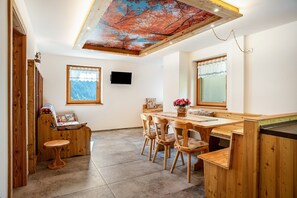 Un interno in legno con zona pranzo, divano e TV a parete.