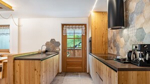 A kitchen with wooden cabinets, a stone backsplash, and a view of greenery outside.