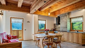 A wooden interior with a dining table, chairs, a sofa, and a kitchen area. - 'Volo Dell'aquila' Apartment with Private Sauna and Mountain Views (Rabbi)