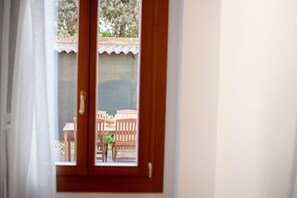 A view through a wooden door with a window, revealing an outdoor seating area with wooden furniture and a small table. - Ca Lion, next Biennale (Venice)