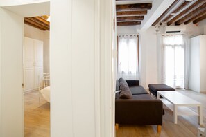 Una habitación moderna y bien iluminada, con techo de madera, un sofá, una mesa y un armario.