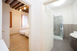 Un dormitorio con suelo de madera, una cama y un ventanal con cortinas.