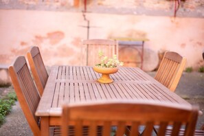 Een houten tafel met vier stoelen en een plant in het midden.