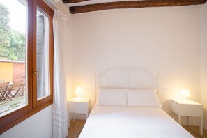 A bedroom with a bed, two bedside tables with lamps, a window with curtains, and a view of an outdoor area with a table and chairs. - Ca Lion, next Biennale (Venice)
