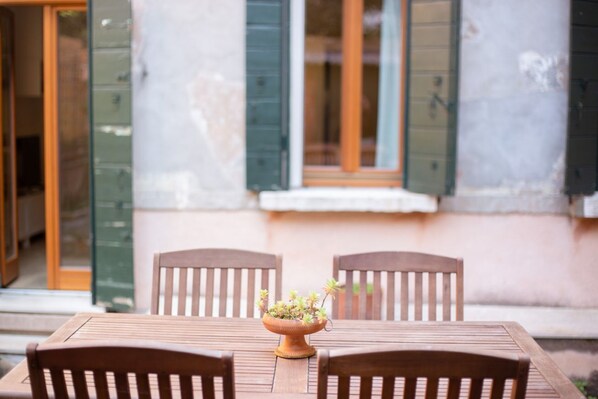 Una mesa de madera con dos sillas y una maceta de terracota con plantas.