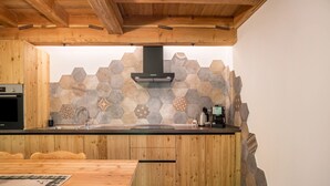 A kitchen with wooden cabinets, a hexagonal tile backsplash, and a built-in stove. - Apartment 'Whisper of the Stream' with Mountain View, Shared Garden and Wi-Fi (Rabbi)