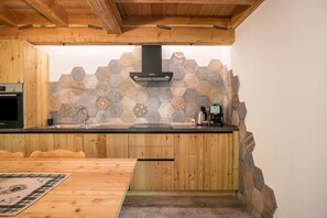 Una cocina con armarios de madera, un salpicadero de azulejos hexagonales y una estufa empotrada.