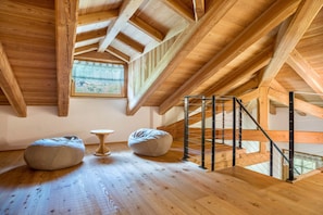 A loft bedroom with wooden beams, a skylight, a staircase, and two bean bags. - Apartment 'Whisper of the Stream' with Mountain View, Shared Garden and Wi-Fi (Rabbi)