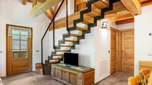 A staircase with wooden steps and black railings, a wooden cabinet with a television, and a wooden door. - Apartment 'Whisper of the Stream' with Mountain View, Shared Garden and Wi-Fi (Rabbi)
