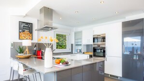 A modern kitchen with a large island, stainless steel appliances, and a view of greenery outside. - Villa 'Azul' with Shared Pool, Wi-Fi and Air Conditioning (Cala Pi)