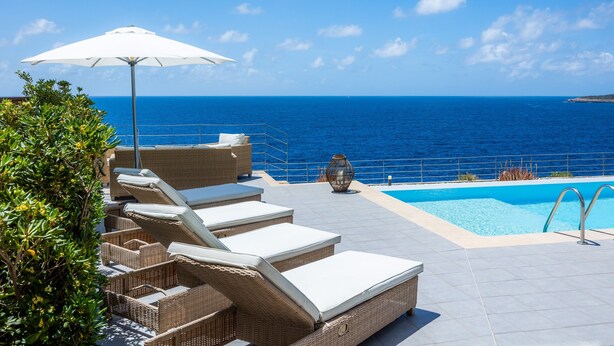 A poolside area with lounge chairs and a view of the ocean. - Villa 'Azul' with Shared Pool, Wi-Fi and Air Conditioning (Cala Pi)
