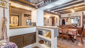 Una cocina con microondas, un lavamanos y una zona de comedor con sillas y una mesa.