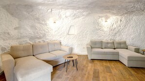 Ein modernes Interieur mit einer Steinwand, zwei Sofas, einem kleinen runden Tisch und Holzboden.