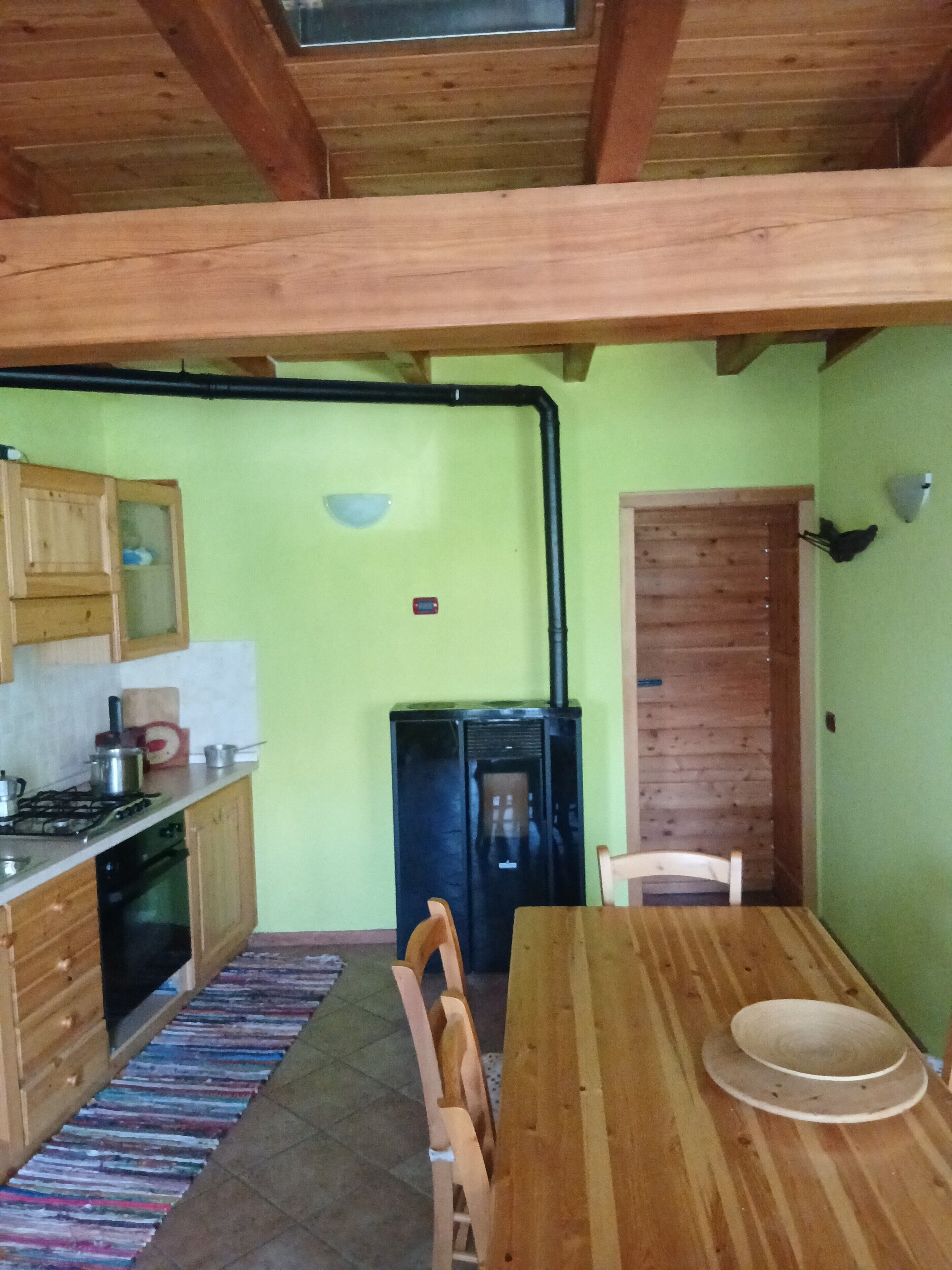 A kitchen with wooden cabinets, a stove, a refrigerator, and a dining table with chairs.