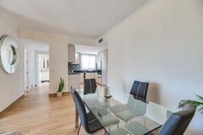 A modern kitchen with white cabinets, a black countertop, and a glass dining table with chairs.