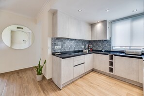 Une cuisine moderne avec des meubles en bois clair, un plan de travail noir et un pare-feu décoratif.