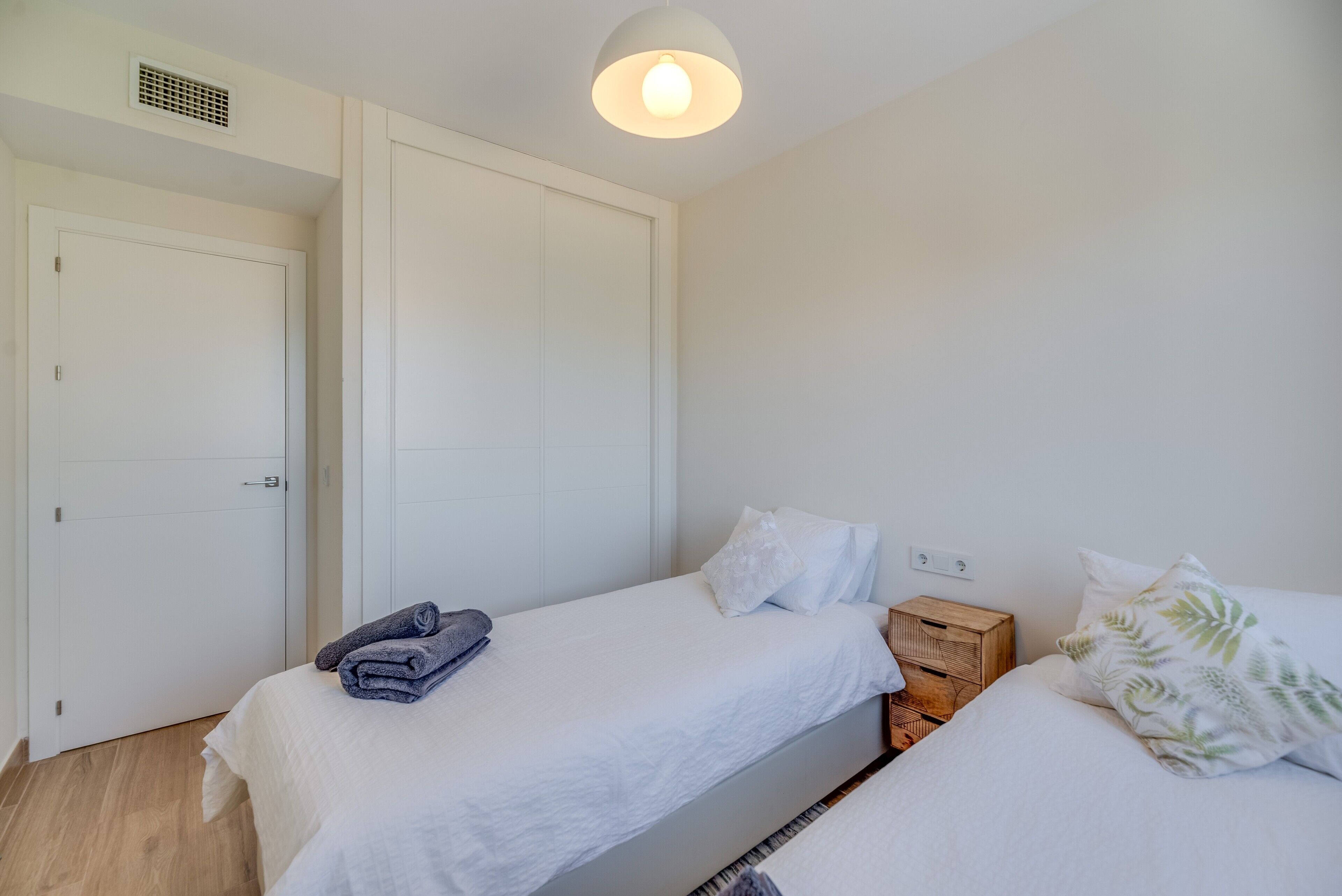 A bedroom with a bed, a nightstand, a wardrobe, and a ceiling light.
