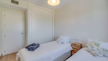 A bedroom with a bed, a nightstand, a wardrobe, and a ceiling light.