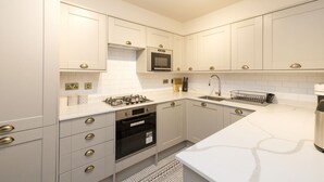 Una cocina moderna con muebles blancos, electrodomésticos de acero inoxidable y un salpicadero decorado.